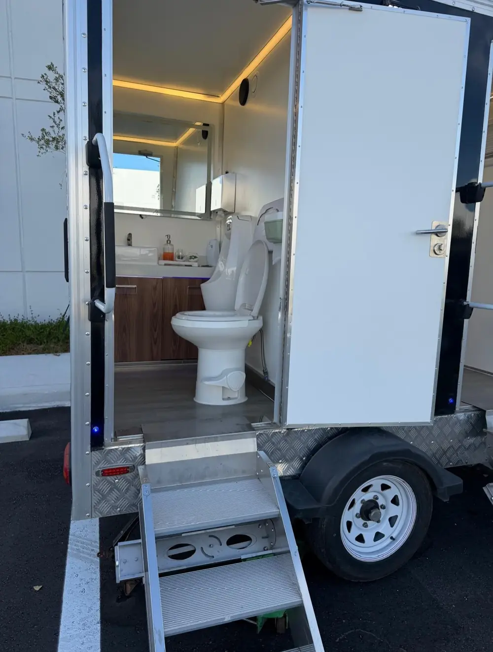 Lit restroom trailer interior with wood vanity and toilet